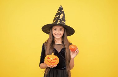 Cadı şapkalı çocuk. Çocuk balkabağını tutuyor. Büyücülük ve büyücülük. çocukluk sonbahar tatili. Kadın sihirbaz. Genç kız kutlamaya hazır. Kostüm partisi eğlencesi. Balkabağı feneri. Mutlu cadılar bayramı