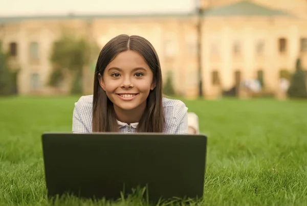 Niño aprendiendo lección privada. bloguear. chica feliz sentado en la hierba verde con el ordenador portátil. Arranca. niño jugando juego de ordenador. de vuelta a la escuela. educación en línea. Día del conocimiento. Divertirse — Foto de Stock