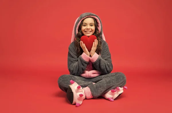 Gelukkig kind in konijn pyjama houden rood hart reddende gift, donatie — Stockfoto