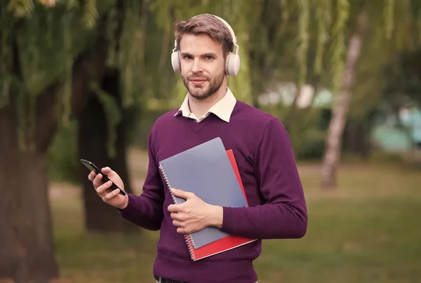 헤드폰을 쓴 남자가 스마트폰으로 음악을 듣고 공원에서 현대 생활을 즐기는 모습 — 스톡 사진