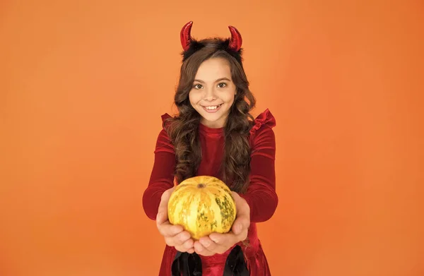 happy child wear devil horns holding pumpkin to create jack o lantern on halloween, selective focus, happy halloween