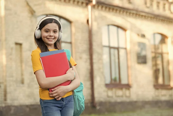 Lächelndes Kind hält Ordner in der Hand. Kinderglück. Mädchen im Headset hören Musik. Wissen aus eBook holen. moderne Schulbildung. zurück zur Schule. glücklich Teenager tragen Arbeitsbuch — Stockfoto