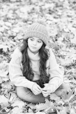 Acele etme. Sonbahar doğasının güzelliği. Mutlu çocuk örgü süveter ve şapka giyer. Genç kız yaprakların arasında dinleniyor. Çocuk sonbahar ormanında yürüyor. Sıcak giysi modası. Mevsimsel hava. çocukluk