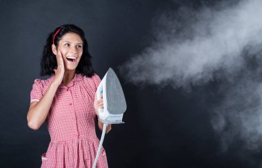 Oda servisi. Manken kız buhar ütüsü kullanıyor. Ev aletleri. Hizmetçi kadın ütü yapıyor. Mutlu ve gülümseyen ev hanımı. Elektrikli ütülü retro kız. Giysileri ütüleyen klasik kadın.
