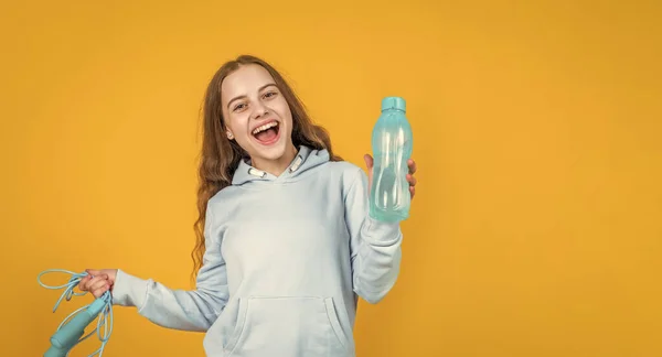 Felice sorridente bambina tenere sport o attrezzature per il fitness di corda da salto e bottiglia d'acqua, salute — Foto Stock