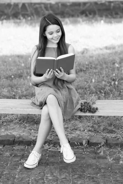 Malá šťastná dívka čtení knihy venku slunečný den, pohádkový koncept — Stock fotografie