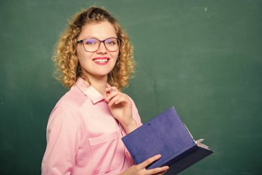 Öğretmen zor konuyu açıkla. Öğrencilerin en iyi öğretmeni. Pedagog kitabı tutuyor ve bilgiyi açıklıyor. Eğitim konsepti. Karatahtanın önündeki kadın öğretmen. Bilgiye karşı tutkulu