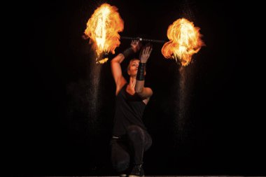 Yüksek enerjili ateş dansçısı. Şehvetli ateş dansçısı karanlıkta alevli bir değnek çeviriyor. Ateş performansı.