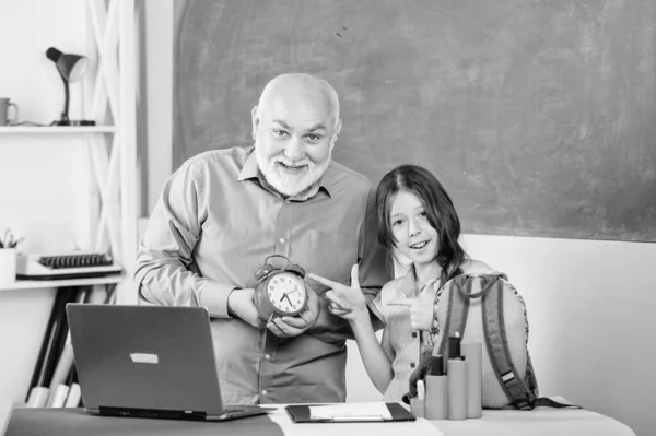 Di giorno. insegnante maturo aiutare allievo con orologio. educazione blogging. Torniamo a scuola. tempo di studiare. lezione di scuola online. piccola ragazza con uomo tutor studio sul computer. allarme di rottura. Buongiorno. — Foto Stock