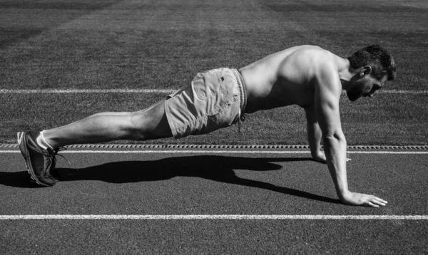 Hombre atlético haciendo flexiones de pie en tablón en el estadio al aire libre, deporte — Foto de Stock