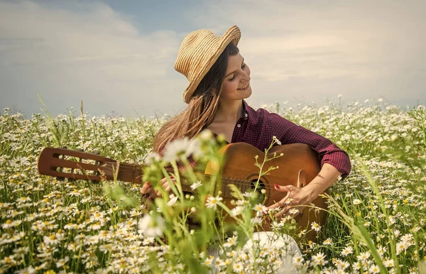 Mutlu kadın papatya tarlasında çiçek topluyor akustik gitar çalıyor, country müzik çalıyor. — Stok fotoğraf