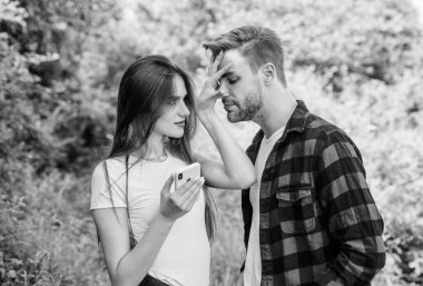 Bakma. Birbirine aşık çiftler. Blog konsepti. Çift açık havada akıllı telefon kullanıyor. Seyir subayı arıyor. İnternette romantik bir randevu. Parktaki kızın telefonunu kurcalayan adam. Kıskançlık. Kişisel alan kavramı. Kayboldum.