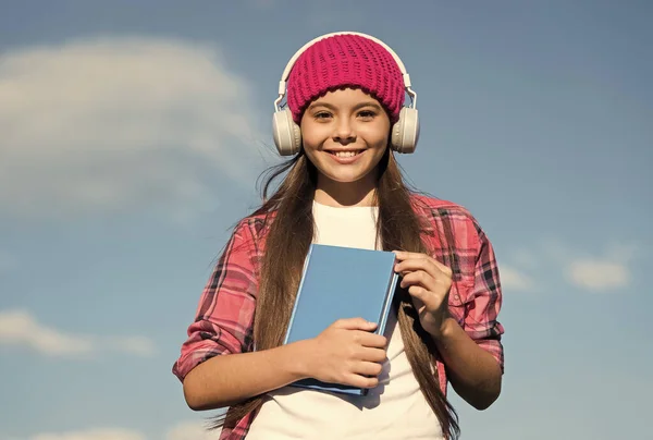 Вивчайте мову по-іншому. Щаслива дитина носить навушники на блакитному небі. Аудіокнига. Навички слухання та читання. Школа іноземних мов. Нова технологія. Приватне викладання. Розбити всі мовні бар'єри — стокове фото