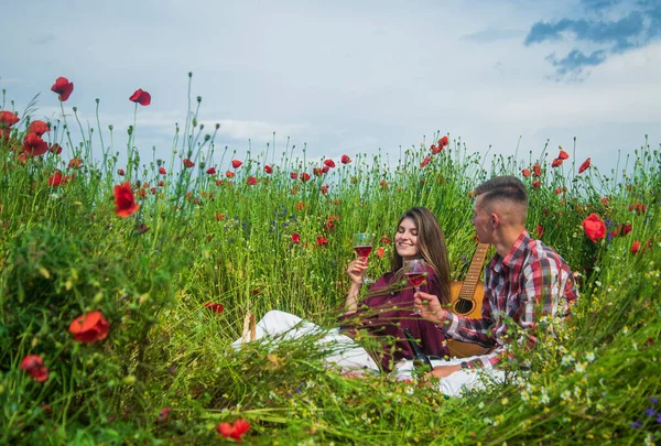 Hombre y mujer teniendo una cita romántica en el campo de flores de amapola con música de guitarra y vino, amor —  Fotos de Stock