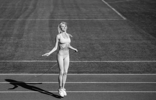 Atleta de deporte femenino en ropa deportiva en el estadio se calienta con saltar la cuerda antes de entrenar fitness, entrenador —  Fotos de Stock