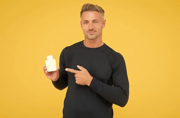 Chico guapo en estilo casual dedo índice de punta presentando producto de perfumería para hombre para aseo y cuidado personal fondo amarillo, señalando — Foto de Stock