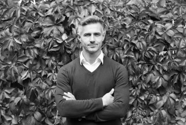 Gerçek güven. Erkek güz mevsimi modası. Sonbahar yaprakları üzerinde yakışıklı bir adam. Erkek güzellik konsepti. Kendine güvenen iş adamları günlük iş kıyafetleri giyerler. Tıraşsız, olgun bir adam.