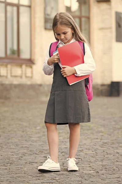 Małe dziecko w formalnym mundurze trzymać książki szkolne na zewnątrz, biblioteka — Zdjęcie stockowe