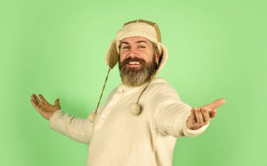 Yüz kılı konsepti. Kürk giysiler. Sakallı hippi. Kuaför salonu. Berber servisi. Sakallı adam kulak flaplı şapka giyer. Kürklü aksesuar. Kış modası. Soğuk hava. Sakal bakımı kış mevsimi