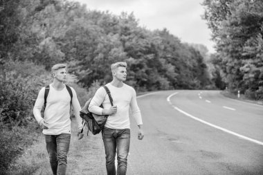 Sırt çantalı bir adam yolda otostop çekiyor. Yaz tatili. Turist gezgini otomobil durağında durur. Bütçe yolcuları. Sırt çantaları yolda beraber yürüyorlar. Yol boyunca yürüyen ikizler. Macera ve keşif