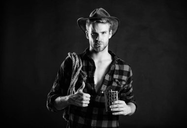 Batı kültürü. Batı hayatı. Şapka tutan ip ve matara giyen adam. Amerikan kovboyunun kementi. Yakışıklı, traşsız, siyah bir kovboy. Şerif kavramı. Vahşi kovboy alkol içiyor.