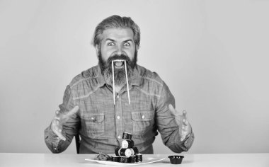 Çubuklu suşi ve zencefil. Japon mutfağı. Japonya 'da geleneksel yiyecekler. Şef yemek servisi. Asya yemeği. Suşi siparişi. Sushi teslimatı. Mutlu adam suşi yer.