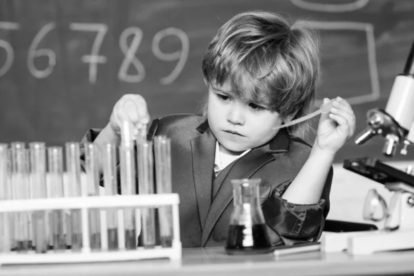 Laboratorium chemiczne. Wracać do szkoły. Dzieciak w fartuchu uczy się eksperymentować na chemii. Mały chłopiec w apteczce. Dzieciak uczy się chemii w szkolnym laboratorium. Pewny swoich badań — Zdjęcie stockowe