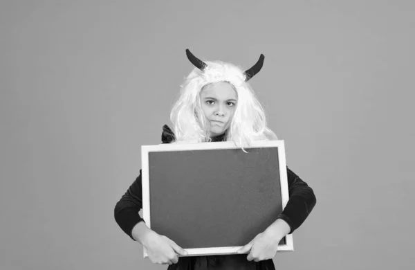Boldogtalan gyerek visel ördög szarv és fehér haj paróka gazdaság iskolai tábla halloween reklám, boldog halloween — Stock Fotó