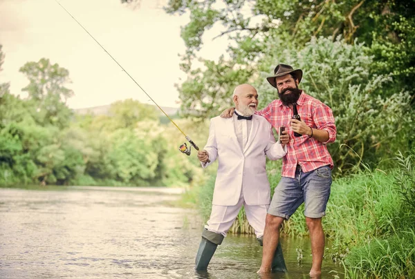 Установите стержень с крючком и раковиной. Рыбалка и питье пива. Бородатый мужчина и элегантный бизнесмен рыбачат вместе. Мужчины расслабляют природу. Веселитесь и расслабляйтесь. Время выходных. Рыбалка — стоковое фото