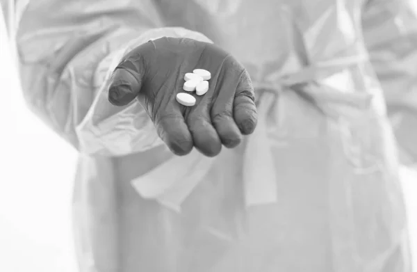 Trabajador médico en traje de protección aislado en píldoras blancas ofrecen medicamentos antibióticos y antipirético de covid19 sarro pandemia virus, remedio coronavirus — Foto de Stock