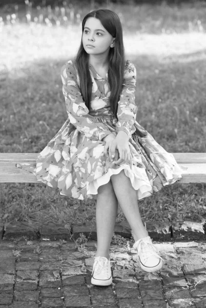 Petite fille aux cheveux longs relaxant dans le parc ensoleillé jour vert fond d'herbe, en attente de quelqu'un concept — Photo