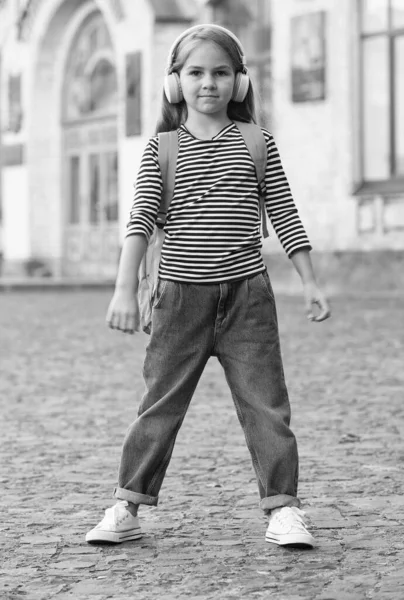 Lindo niño llevar bolsa de viaje escuchando música en los auriculares modernos urbanos al aire libre, viajar —  Fotos de Stock