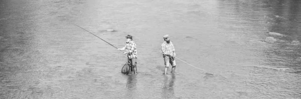 Sommerwochenende. Glücklicher Fischer mit Angel und Netz. Hobby und sportliche Aktivität. Gemeinsam angeln. Männer stehen im Wasser. Angeln ist viel mehr als Fisch. Männerfreundschaft. Vater und Sohn angeln — Stockfoto