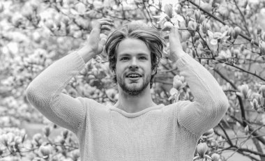 Taze çiçek. Sakura arka planı. İyi havanın tadını çıkar. Çiçek açan seksi adam. Bahar modası. Erkek cinselliği. traşsız erkek manolya ağacı. Bahar tazeliği