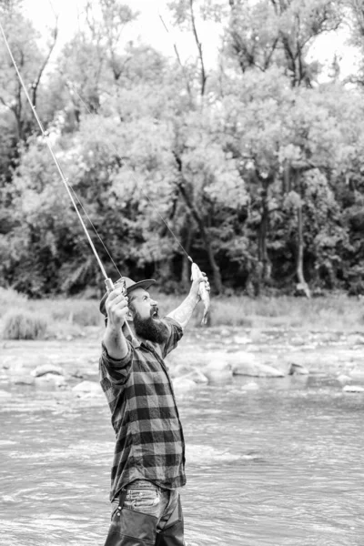 Celebrar el éxito. fin de semana de verano. Feliz pesca con mosca. hombre maduro pesca con mosca. hombre pescando peces. pescador mostrar técnica de pesca uso de la caña. Pescador barbudo en el agua. pasatiempo y actividad deportiva — Foto de Stock