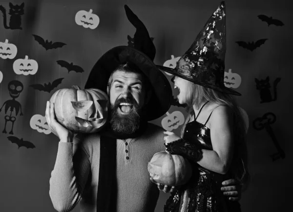 Czarodziej i mała czarownica w czarnych kapeluszach trzymać dynie. — Zdjęcie stockowe