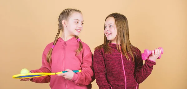 Sur le chemin de la forme parfaite. Enfants heureux avec du matériel sportif. entraînement de gymnastique des adolescentes. Raquette de tennis et ballon d'activité. Petite fille. Haltère de fitness. Succès sportif. Choisir le meilleur — Photo