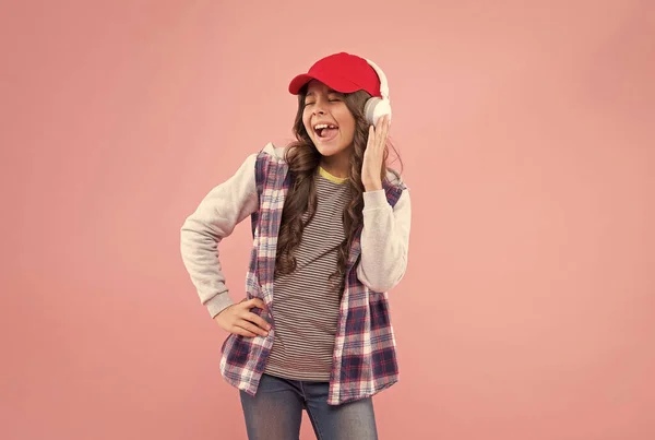 Allegra bambina con i capelli ricci ascoltare musica in cuffia, nuova tecnologia — Foto Stock