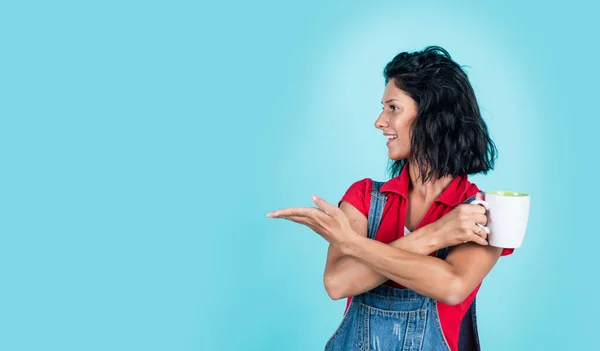 Mira aquí. belleza atractiva con taza o taza. expresar emociones humanas. bebiendo para refrescarse. mujer feliz presentando producto, espacio de copia. chica en camisa y jeans beber té. bebida de café por la mañana —  Fotos de Stock