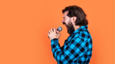 Bıyıklı ve sakallı yakışıklı hippi karaokede şarkı söylüyor.