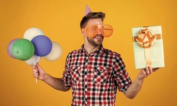 Alles Gute zum Geburtstag. Männerweihnachtsfeier. bärtiger Typ mit Party-Luftballons und Geschenkbox. Der unrasierte, gutaussehende Mann mit der Borste feiert geschäftlichen Erfolg. Ausdruck puren Glücks — Stockfoto