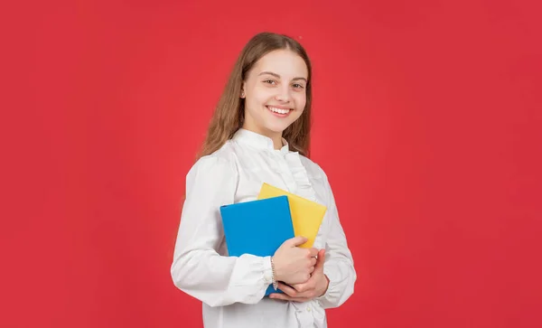 Glückliches Kind in weißem Hemd bereit zum Lernen Hausaufgaben mit Buch auf rotem Hintergrund, Schule — Stockfoto