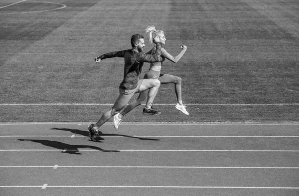 Homem atlético e mulher sexy competir em sprint. Treinador masculino e feminino na pista de corrida do estádio. estilo de vida saudável. velocidade da maratona. casal esporte correr rápido para ganhar. molinetes fitness de sucesso — Fotografia de Stock