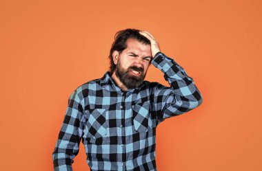 Kötü hissediyorum. Kareli gömlekli sakallı adam. Sıradan bir adam insani duygularını ifade eder. Uzun saçlı ve bıyıklı hipster 'ın başı ağrıyor. Erkek güzellik ve moda. Migren konsepti. Acı çekiyorum.