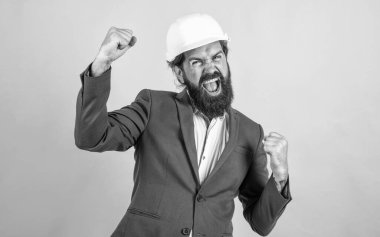 Kasklı, sakallı ve bıyıklı başarılı bir adam inşaat alanında iş adamı gibi görünüyor, başarıyı kutluyor.