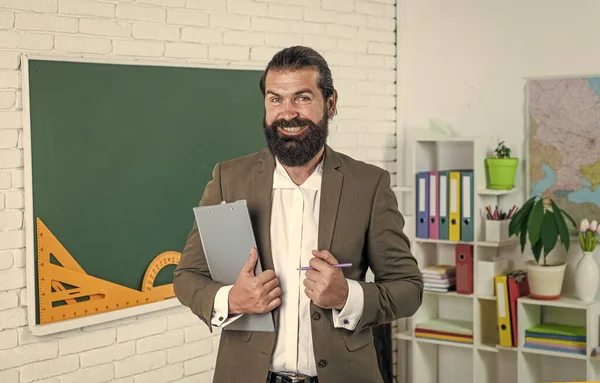 Взрослый бородатый учитель в костюме сидит в классе с доской, учится — стоковое фото