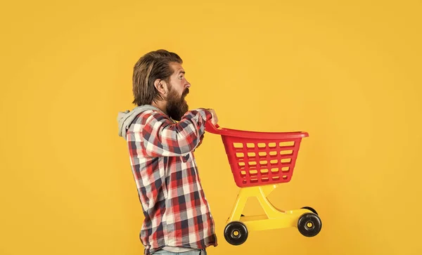 A montar um carrinho de compras. homem engraçado com carrinho de compras pequeno. fim de semana na compra de produtos. alegra compras bem sucedidas. brutal maduro hipster ir às compras. Está na hora de encher o carrinho. homem ir às compras — Fotografia de Stock