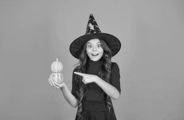 Chica adolescente con sombrero de bruja celebrar Halloween. Feliz Halloween. truco o tratar el concepto. Carnaval disfraz festivo de bruja. niño señalando con el dedo a la pequeña calabaza. niño celebrar vacaciones de otoño —  Fotos de Stock