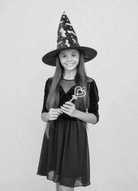 Mutlu çocuk cadı şapkası takar sihirli değnek tutar Cadılar bayramında büyü yaratmak için, mutlu cadılar bayramı