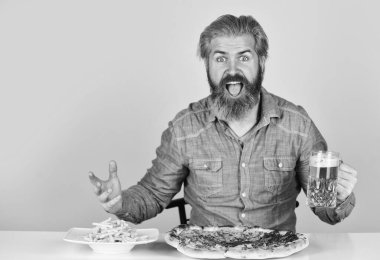 Pizza partisi konsepti. Büyük porsiyon. Cuma geleneği. Barda akşam yemeği. Aç adam pizza yiyecek ve bira içecek. Sonunda pizza zamanı. Pizzacı. Neşeli sakallı hippi adam pizza yiyor.